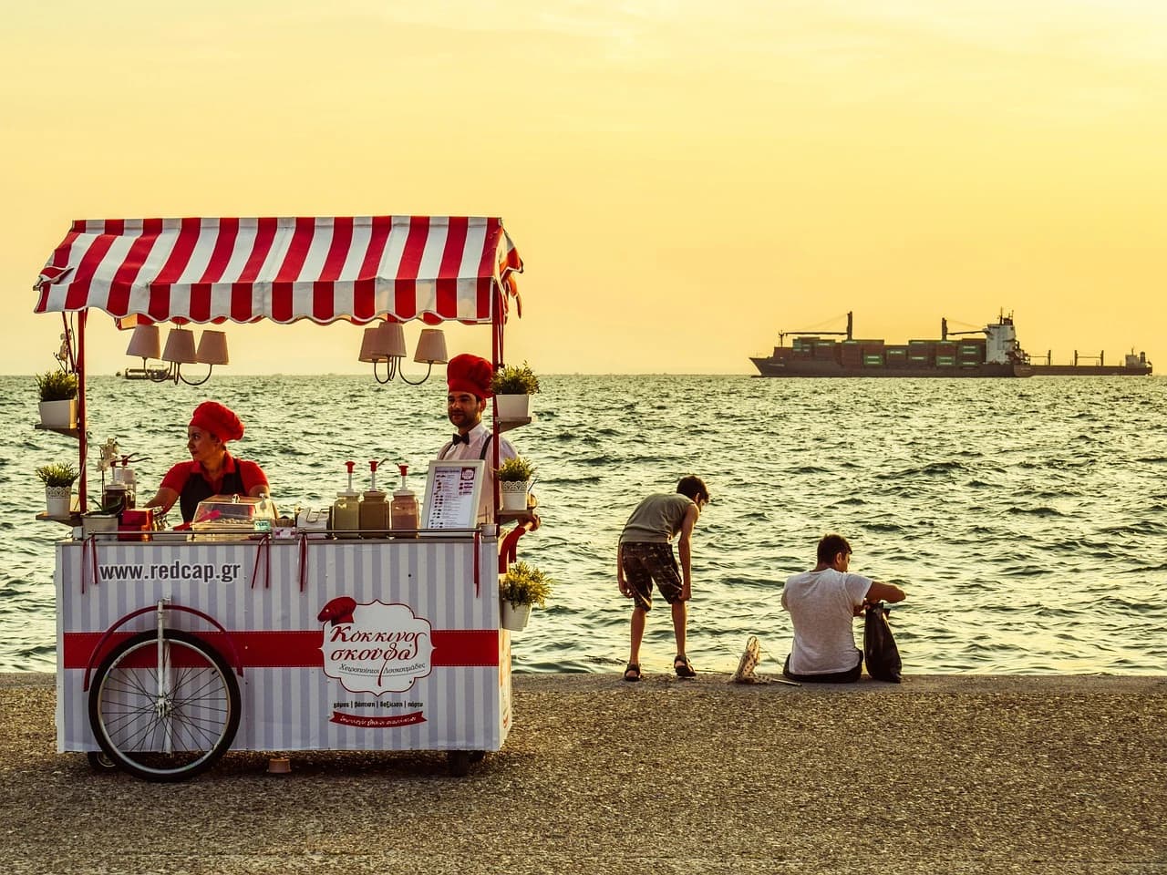 A historic city street in Thessaloniki is filled with bustling cafes and restaurants with outdoor seating.